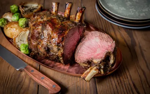 Carré d'agneau rôti 1 kg, saignant, servi avec des oignons et des choux de Bruxelles. Le temps de cuisson est parfait.