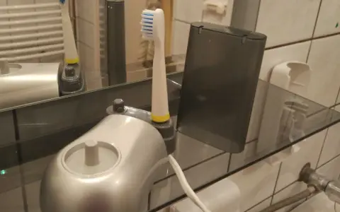 Pierwsze ładowanie szczoteczki elektrycznej. Nowa szczoteczka z ładowarką i etui na półce w łazience.