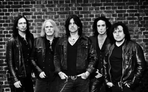 Les membres de Black Star Riders posent devant un mur de briques.