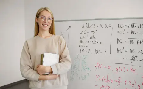 Uśmiechnięta nauczycielka z zeszytem przy tablicy z matematycznymi wzorami. Zastanawia się, ile punktów na maturze z matematyki można zdobyć za takie zadania.