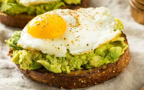Tostada integral con aguacate machacado y huevo frito, un delicioso desayuno keto.