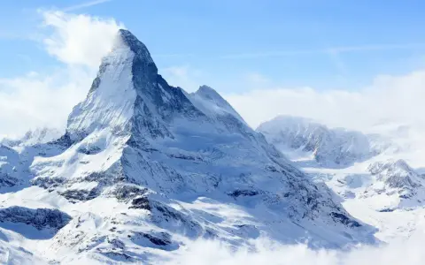 Majestatyczny, ośnieżony szczyt Matterhorn, jeden z najwyższych szczytów Europy, wyłania się z chmur.