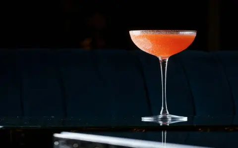 Orzeźwiający el presidente cocktail, z pomarańczowym odcieniem i cukrową obrączką, stoi na błyszczącym blacie.