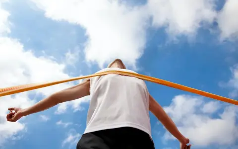 Atleta taglia il traguardo, la fatica della maratona km è ripagata. Cielo azzurro e nuvole bianche.