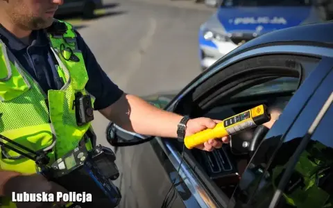Policjant z Lubuskiej Policji bada kierowcę alkomatem. Za jazdę po alkoholu, nawet 1 promil, prawo jazdy jest zabierane.