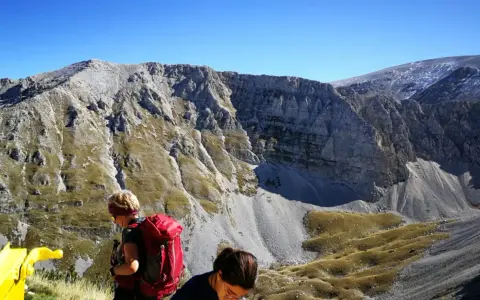 Escursionisti con zaini rossi ammirano il panorama montuoso vicino al bivacco Fusco.