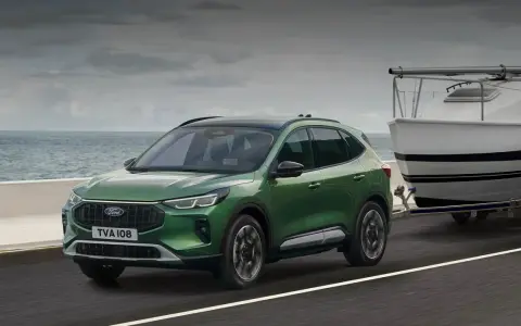 Zielony Ford Kuga z przyczepą i łodzią, idealny na wakacyjne wyjazdy. Sprawdź ford kuga cena!