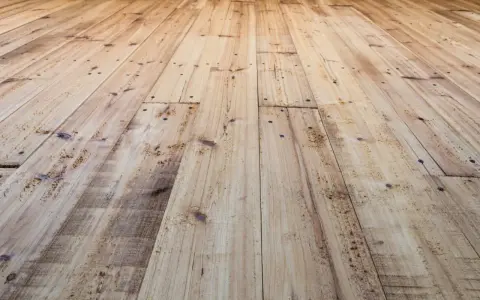 Planches de bois clair, usées et clouées, avec un parquet qui craque sous les pieds.