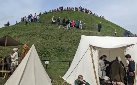 Ludzie wchodzą na Kopiec Kraka, a u jego podnóża rozstawiono historyczne namioty.