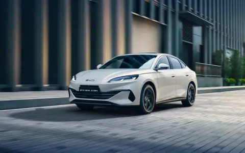 Biały sedan BYD Seal 6 DM-i jedzie po miejskiej ulicy.