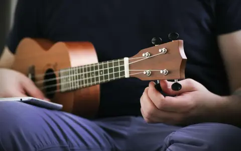 Osoba stroi ukulele, korzystając z aplikacji do nauki gry.