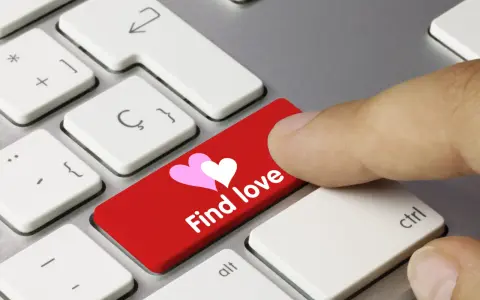 Palec naciska czerwony klawisz z sercami i napisem "Find love", symbolizując bezpieczne randki online.