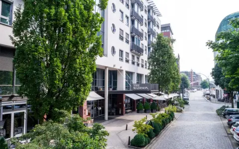 Das Madison Hotel Hamburg mit Außenbereich und Blick auf eine kopfsteingepflasterte Straße.