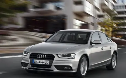 Srebrne Audi A4 B8 w ruchu miejskim, znane z typowych usterek, pędzi ulicą.