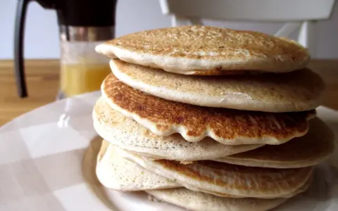 Pila di soffici pancake con farina di avena, dorati e invitanti, pronti per una colazione sana e gustosa.