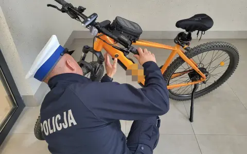 Policjant sprawdza, czy na rower elektryczny trzeba mieć prawo jazdy. Pomarańczowy rower z silnikiem.