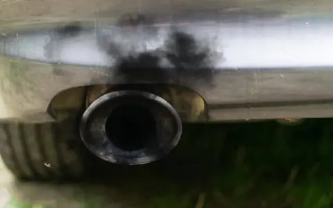 Zanieczyszczony układ wydechowy samochodu, czarny dym wydobywa się z rury. Czas na czyszczenie DPF.