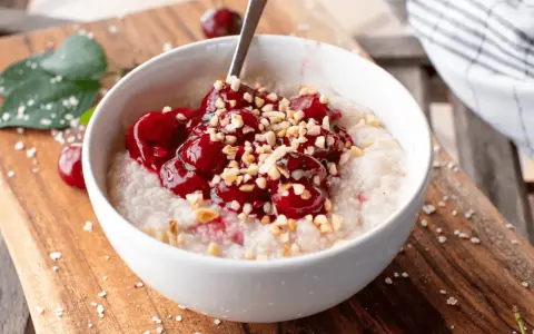 Una ciotola di porridge con ciliegie e nocciole tritate, una deliziosa colazione senza zuccheri.