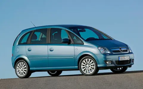 Błękitny Opel Meriva A z przyciemnianymi szybami stoi na tle błękitnego nieba.