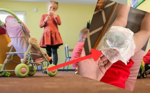Dziecko w pampersie, obok wózek dla lalek i inne dzieci bawiące się w pokoju.