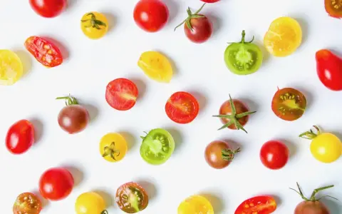 Un assortiment coloré de meilleures tomates cocktail, entières et coupées, sur fond blanc.