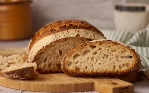 Ein frisch gebackenes reines Emmerbrot, aufgeschnitten auf einem Holzbrett. Die Krume ist luftig und goldbraun.