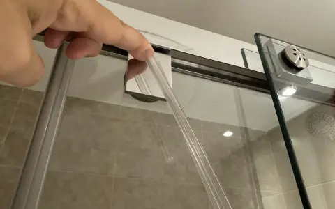 Mano insertando una goma nueva para cambiar gomas mampara ducha.