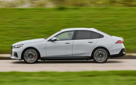 Ein grauer BMW 550e fährt auf einer Straße, die Landschaft verschwimmt im Hintergrund.