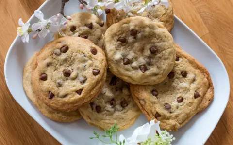 Schokoladenkekse, die an das Subway Cookies Rezept erinnern, auf einem Teller mit Kirschblüten.