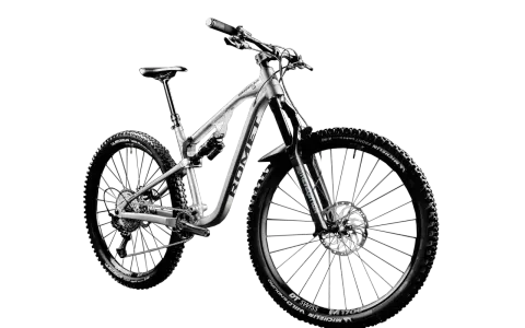 Srebrny rower górski (MTB) z pełnym zawieszeniem, szerokimi oponami Michelin Wild Enduro i amortyzatorem Rock Shox. Idealny na trudne trasy, nie crossowy.