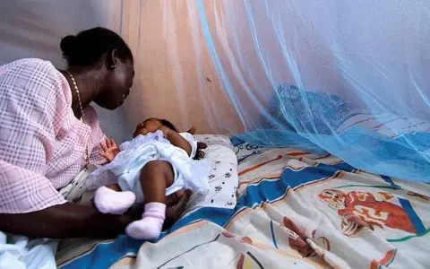 Mor och barn under myggnät, skyddade från malaria. Bali är en plats där kampen mot malaria fortsätter.
