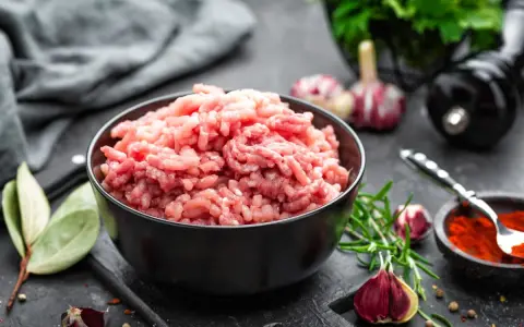 Mielone mięso w misce, gotowe na coś fajnego z mięsa mielonego. Obok czosnek, rozmaryn i przyprawy.