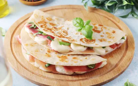 Piadina come farcirla: prosciutto, mozzarella filante e basilico fresco, un'idea gustosa e veloce.