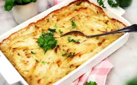 En krämig Janssons frestelse i en vit form, redo att serveras. Perfekt för ett julbord eller en mysig middag.