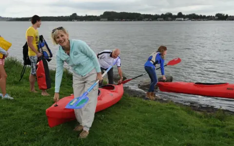 Familie bereitet sich auf einen Aktivurlaub an der Ostsee vor, holt Kajaks und Paddel aus dem Wasser.