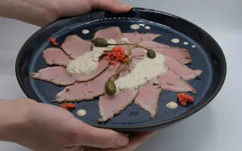 Vitello Tonnato: hauchdünne Scheiben Kalbfleisch, belegt mit cremiger Thunfischsauce, Kapern und roten Kaviar-Kügelchen.