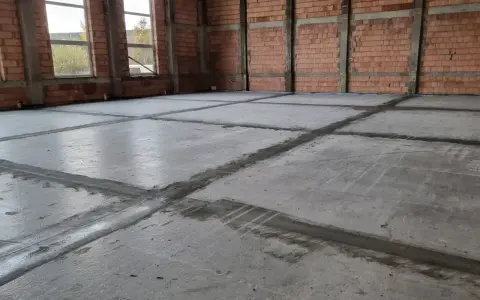 Surowa posadzka w budowie, podzielona na kwadraty. Widać linie fugowania, które pomogą obliczyć, ile potrzeba wylewki samopoziomującej na m2.