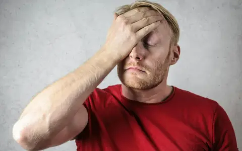 Uomo con mano sulla fronte, occhi chiusi, espressione di stress. Possibili sintomi di attacchi epilettici da stress.