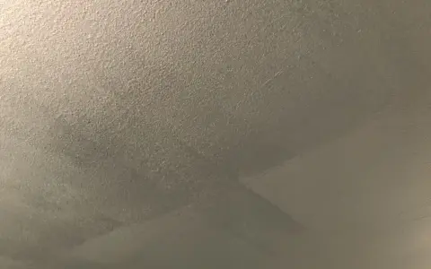 Ett flammigt tak efter målning, med synliga penseldrag och en textur som påminner om sand.