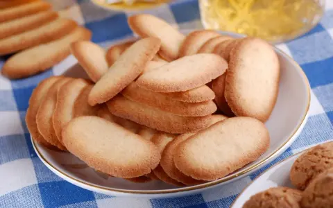 Un piatto pieno di croccanti lingue di gatto, perfette per accompagnare un tè o un caffè.