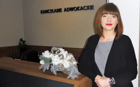 Kobieta w czarnym żakiecie przy recepcji z dekoracją kwiatową. Napis "KANCELARIE ADWOKACKIE".
