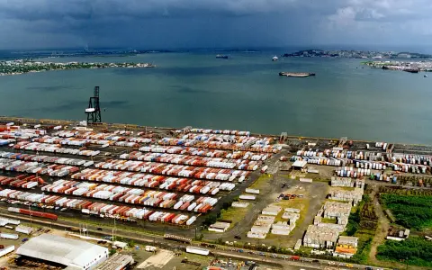 Vasto deposito di container nel porto di San Juan, Porto Rico, con navi in lontananza sotto un cielo nuvoloso.