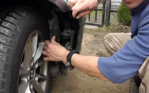 Naprawa awarii PDC BMW. Mężczyzna demontuje fragment nadkola, by dostać się do czujników parkowania.