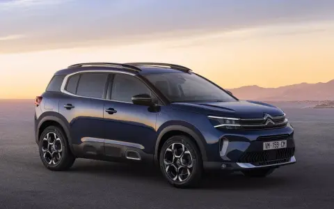 Ciemnoniebieski, kompaktowy SUV Citroën C5 Aircross na tle zachodzącego słońca nad morzem.