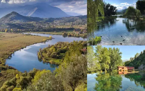 Paesaggio incantevole del lago di Posta Fibreno, con montagne sullo sfondo, un fiume serpeggiante e un antico mulino rosso riflesso nelle acque cristalline.