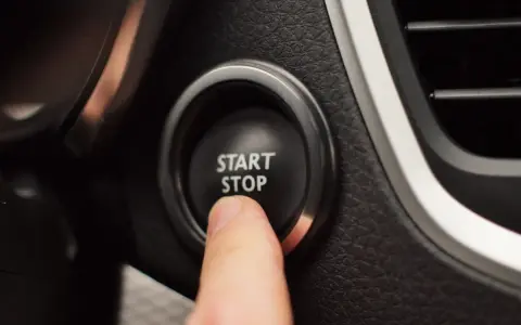 Palec naciska przycisk START STOP w samochodzie, rozpoczynając lub kończąc podróż.