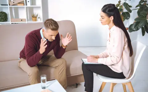 Mężczyzna rozmawia z psychologiem, siedząc na kanapie.