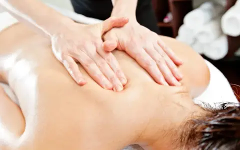 Hands perform a relaxing massage on a person's back, evoking the gentle pressure of shiatsu massage vs deep tissue.