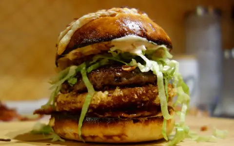 Apetyczny burger drwala przepis: podwójna wołowina, chrupiący panierowany kotlet, sałata i sos na puszczy.
