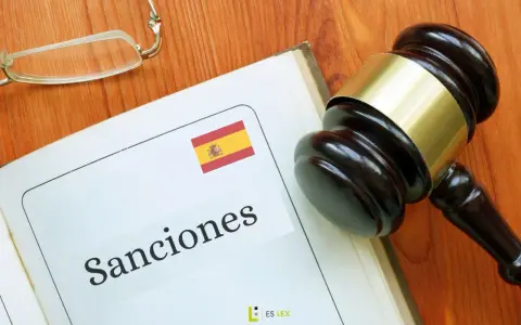 Martillo de juez sobre libro abierto con la palabra "Sanciones" y la bandera de España. Podría ser una multa hacienda.